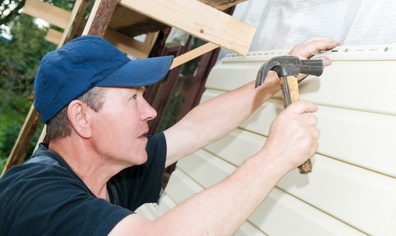 Worker installing siding on home