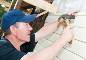 Worker installing siding on home